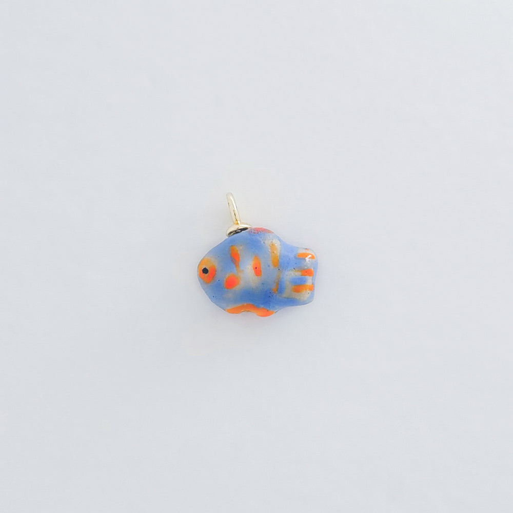 Fish-shaped charm with blue and orange design on a light gray background