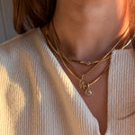 Close-up of a person wearing multiple gold necklaces with pendants