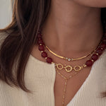 Close-up of a woman wearing gold and red beaded necklaces.