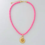 Neon pink necklace with a gold shell pendant on a light gray background