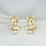 Pair of gold floral earrings on a light gray background