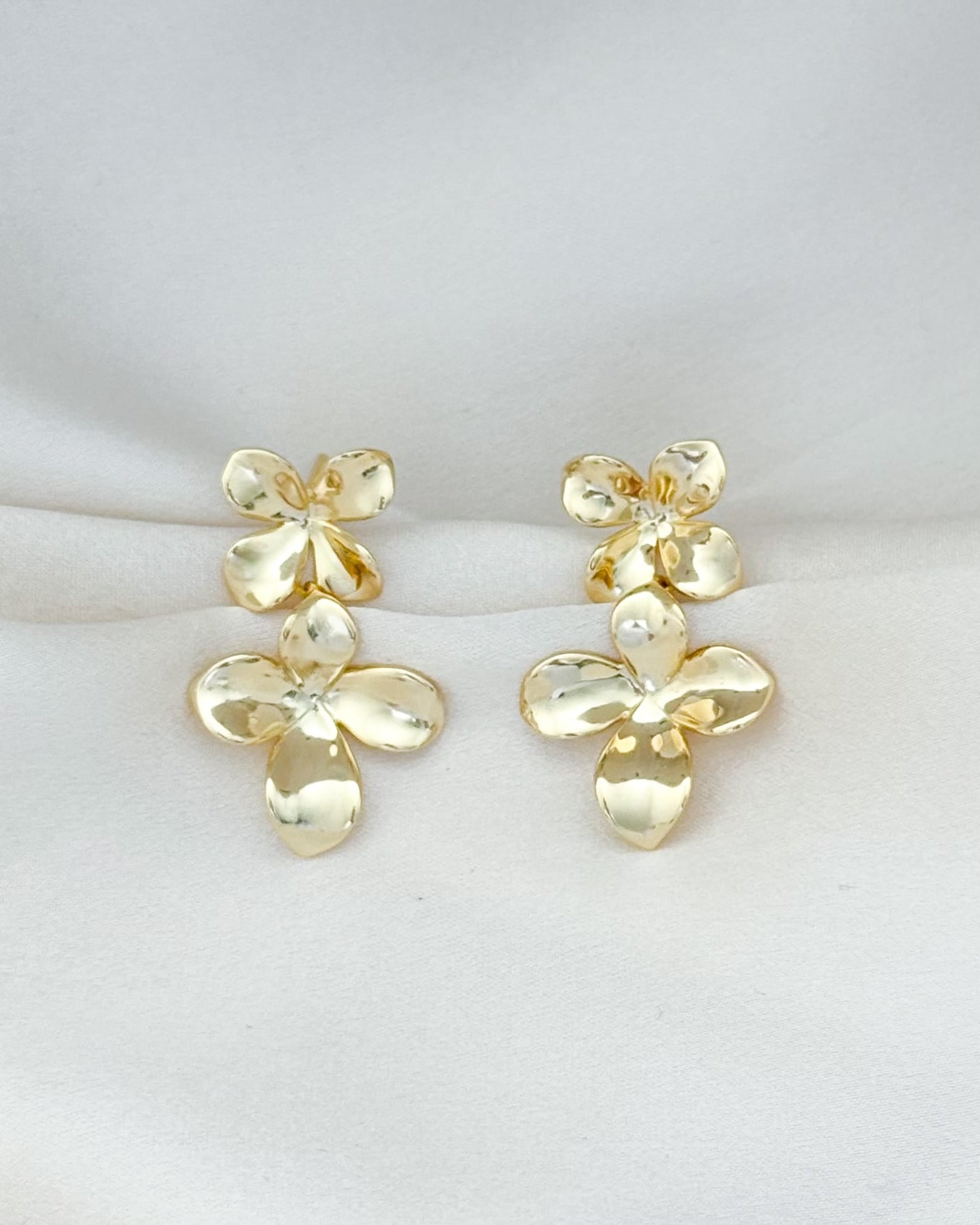 Pair of gold floral earrings on a light gray background