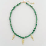 Necklace with green beads and three gold fish charms on a light gray background