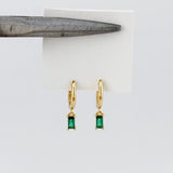 Gold earrings with green gemstones on a white card