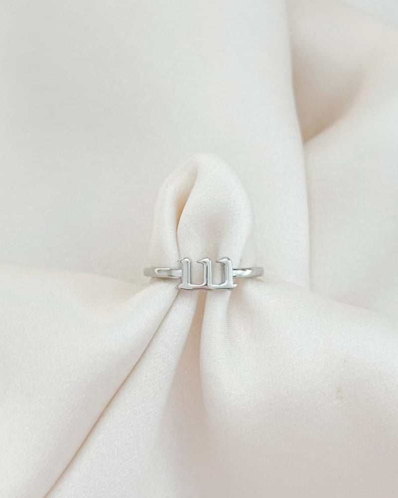 Silver ring with a unique design on a soft white fabric background