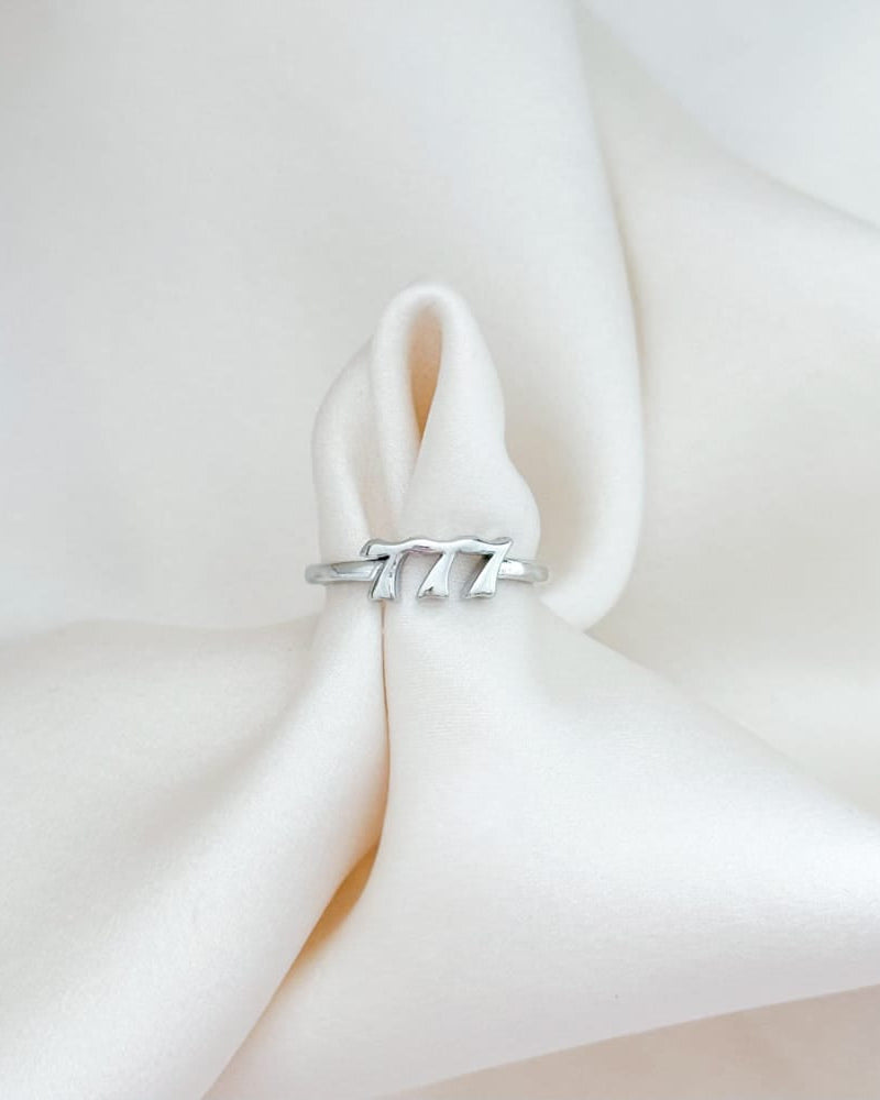 Silver ring with a mountain design on a soft white fabric background