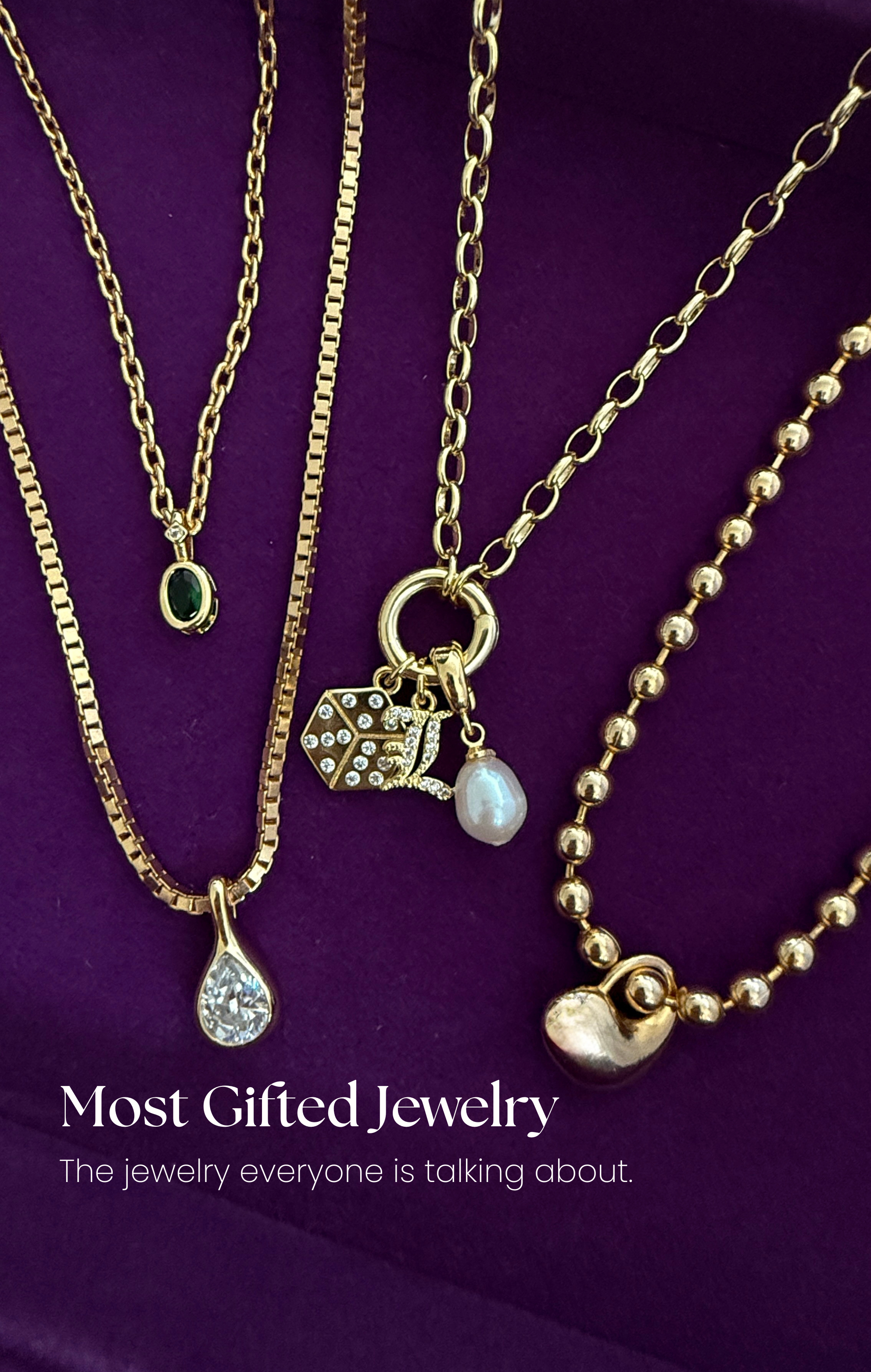Three gold necklaces with various charms on a purple background
