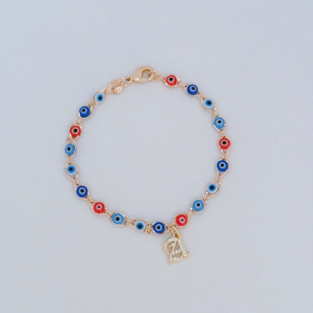 Bracelet with colorful evil eye beads and gold initial charm on light background