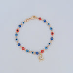 Bracelet with colorful evil eye beads and gold initial charm on light background