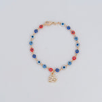 Bracelet with colorful evil eye beads and gold initial charm on light background