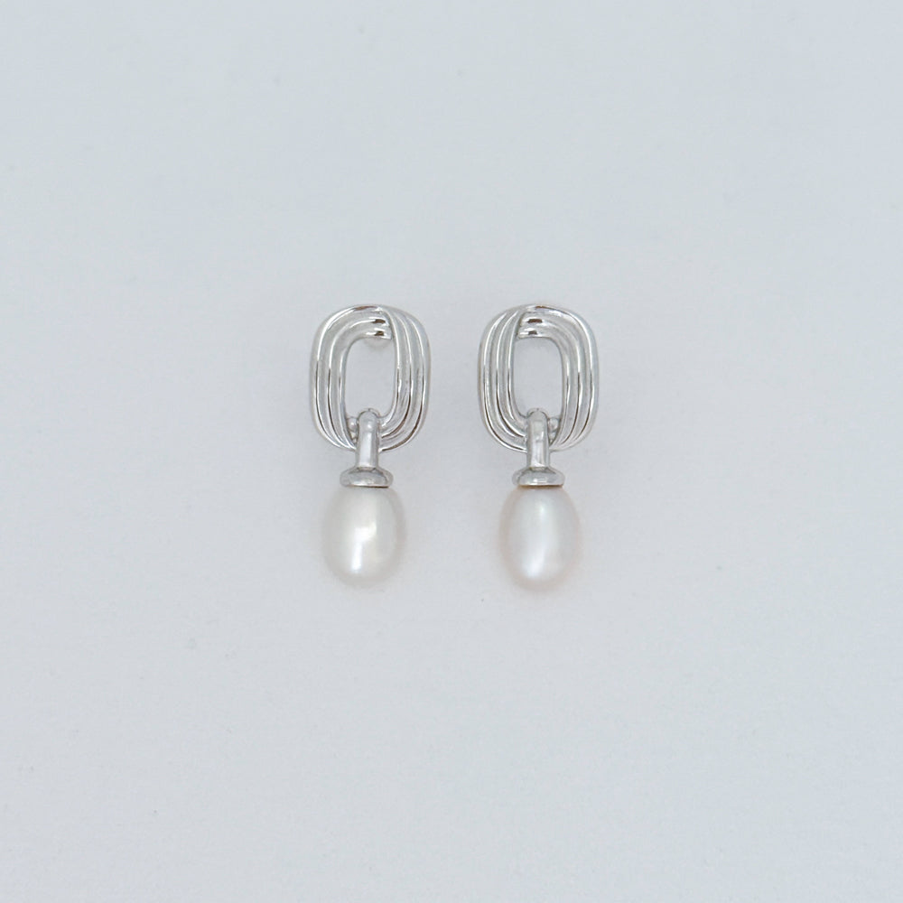 Sterling silver drop earrings with abstract rectangular links and freshwater pearl drops, displayed on a light gray background.