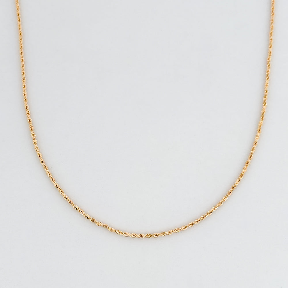 Gold rope chain necklace on a light gray background