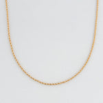 Gold rope chain necklace on a light gray background