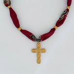 Statement necklace with stainless steel cross pendant and red patterned bandana wrap, displayed flat on a light gray background.