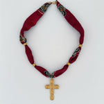 Red scarf fabric necklace with gold cross pendant on a white background