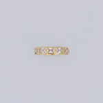 Gold ring with square-cut gemstones on a light gray background