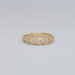 Gold ring with square-cut gemstones on a light gray background