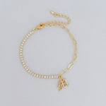 Gold bracelet with diamond accents and a letter charm on a light gray background