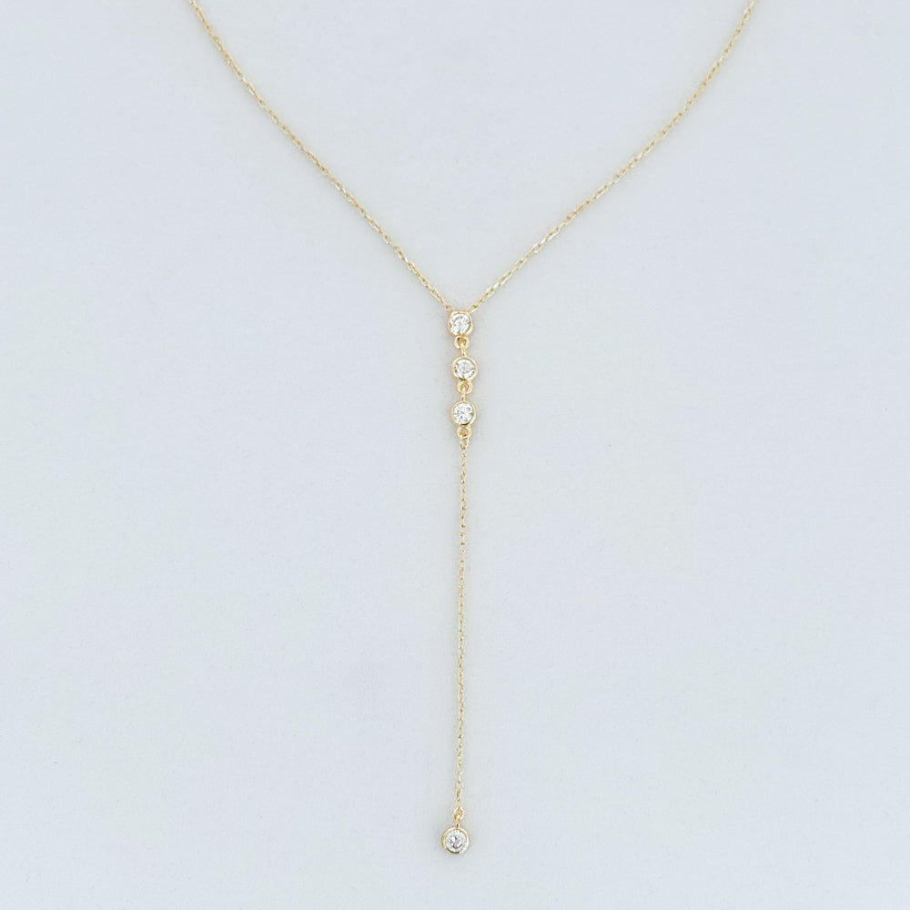 Gold y-necklace with small round pendants on a light gray background