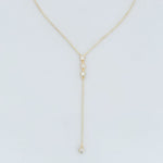 Gold y-necklace with small round pendants on a light gray background